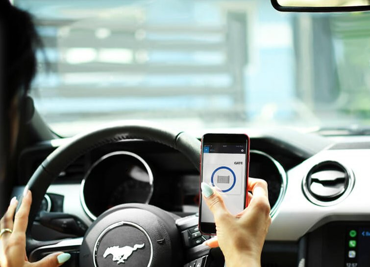 BleBox gateBox - otwieranie bramy przez telefon BleBox gateBox: Kobieta otwiera bramę garażową kodem QR z telefonu w samochodzie Ford Mustang. Bezkluczykowy dostęp.