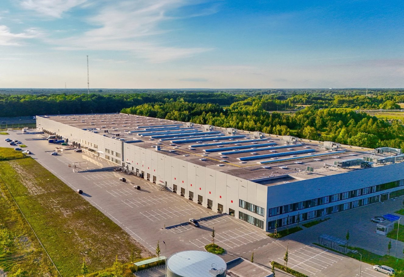 Budynek magazynowy lub hala logistyczna z instalacjami technicznymi w tle